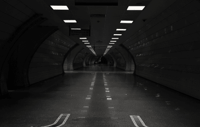 A picture of a road within a tunnel with symmetrical lighting on the top.