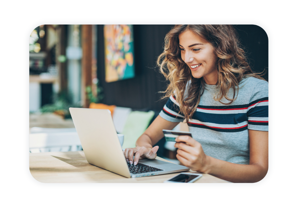 A woman holds her credit card while she looks at her laptop