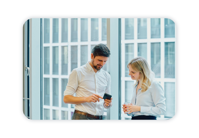 Two colleagues talking and looking at a smartphone.